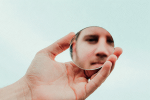 Visage vu à travers un miroir, symbole de dépersonnalisation et de perte de repères dans le burnout.